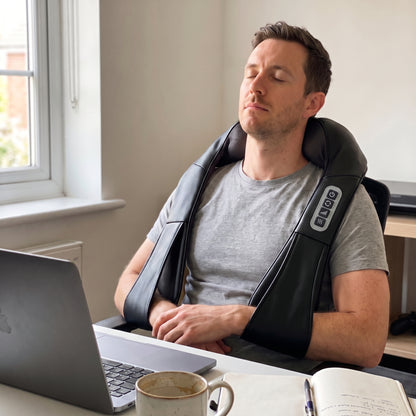 A man taking a break from his desk wearing the Velto Neck & Shoulder Massager